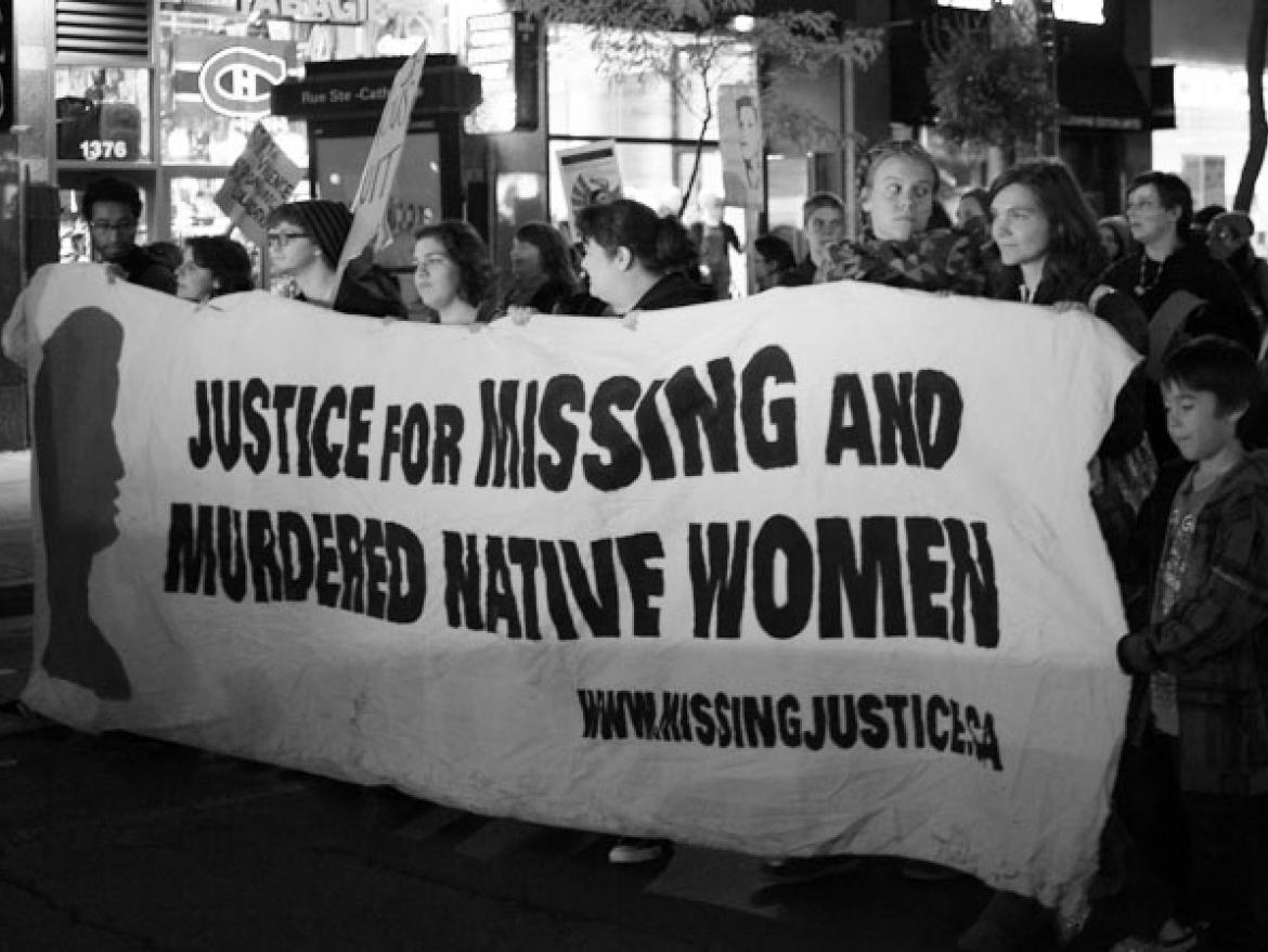 Marchers carrying a sign that says "Justice for Missing and Murdered Native Women"