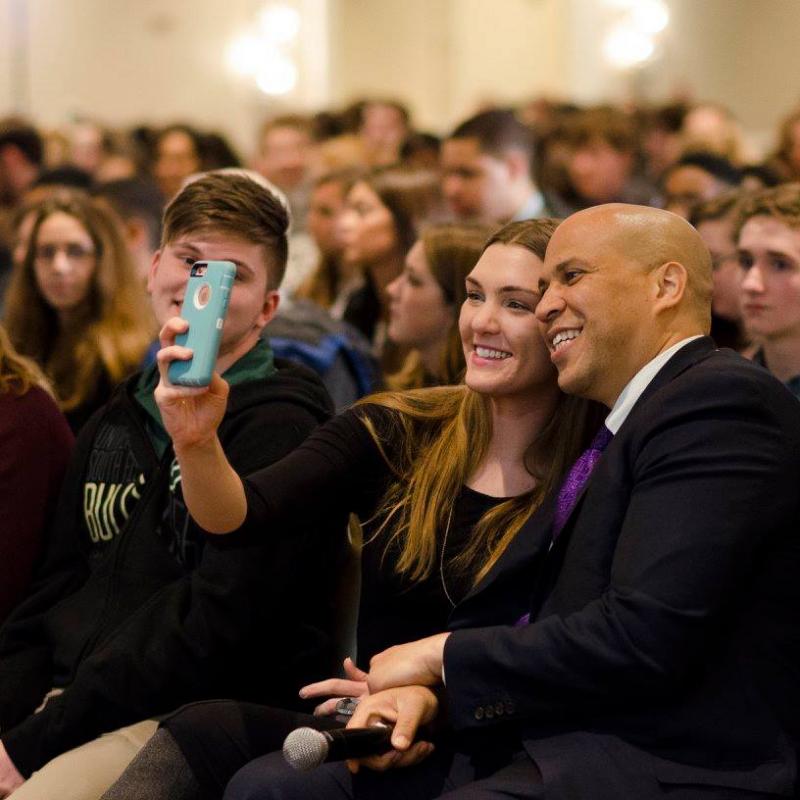 Cory Booker takes a selfie with a young adult