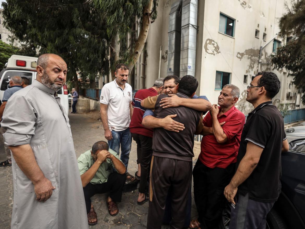 A group of Palestinian men embrace in the aftermath of an Israeli airstrike in Gaza in October 2023. 