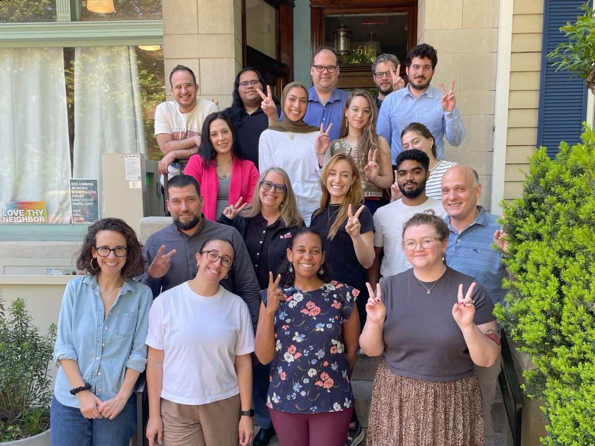 A group of people on the steps facing the camera and making peace signs