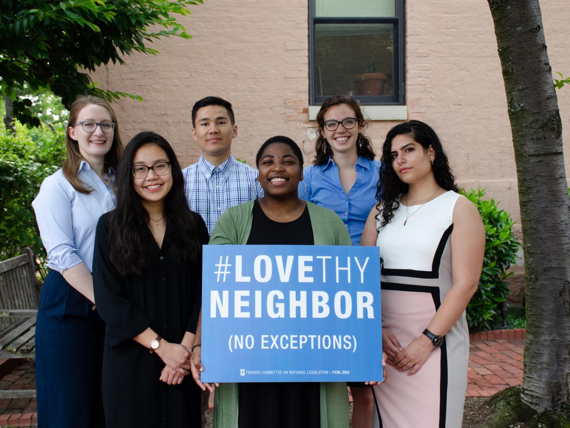 the 2019 summer interns in two rows, in front of 245 2nd Street, holding a "Love Thy