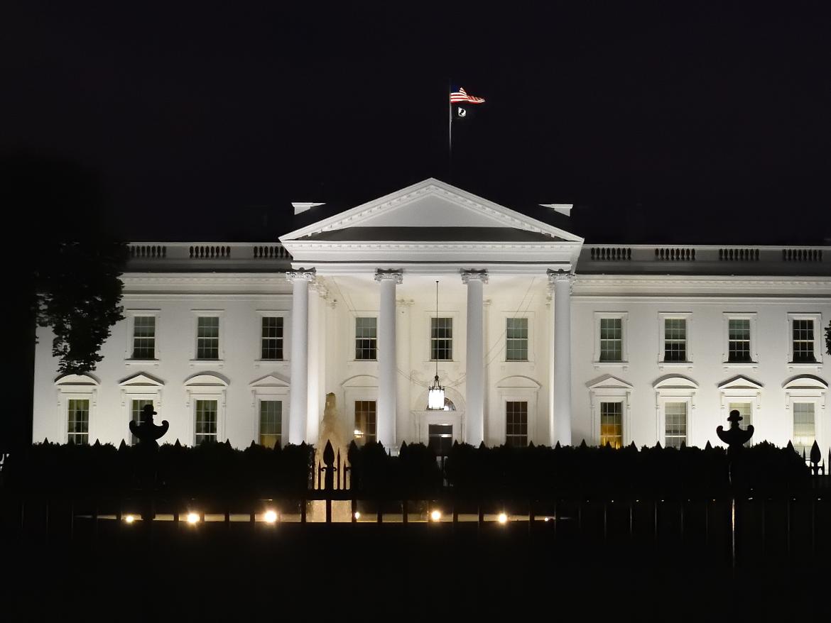 The White House is shown lit up against a dark background.